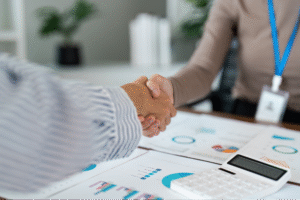 Business handshake over analytics reports, symbolizing collaboration and strategic insights.