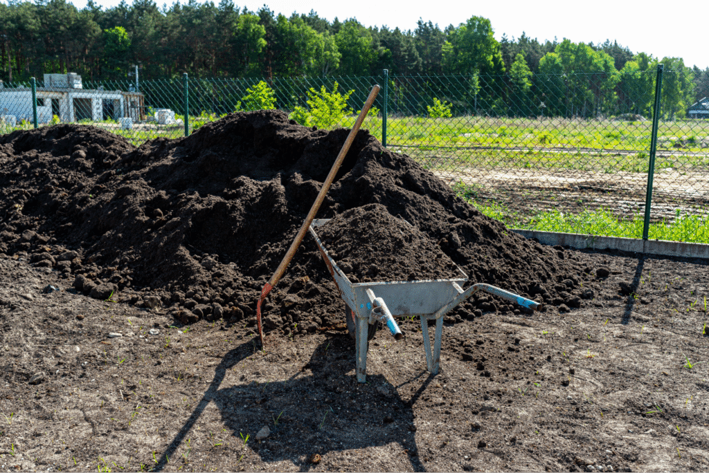 Wheelbarrow and tools ready for soil preparation in a garden setting.