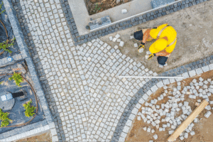 A worker skillfully lays cobblestones to create a new pathway.