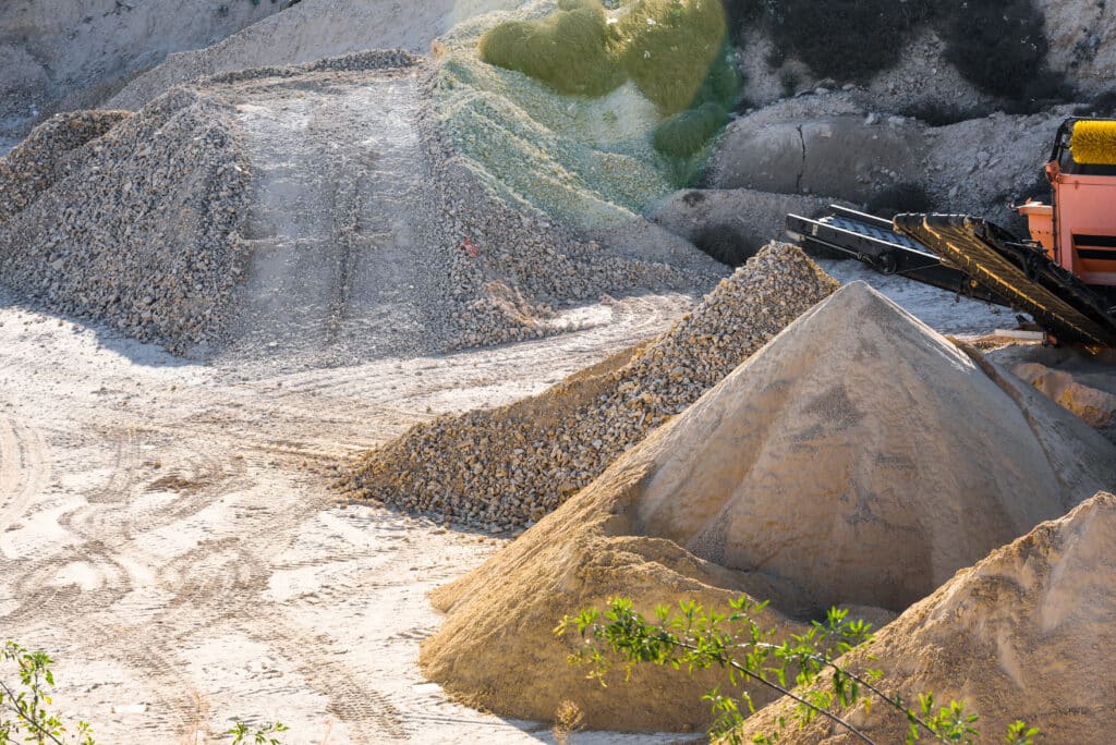 Conveyors transporting crushed sand and rubble in a gravel quarry landscape.