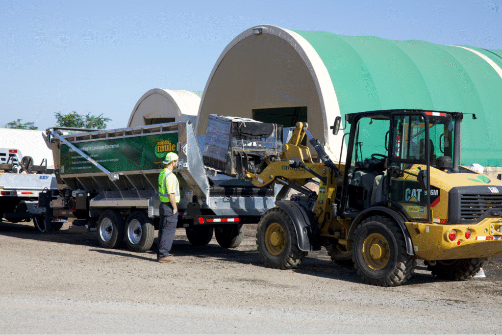 Loader efficiently unloading materials at a job site with the Mulch Mule trailer.