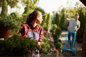Gardening couple smiling and working together in a vibrant plant nursery.