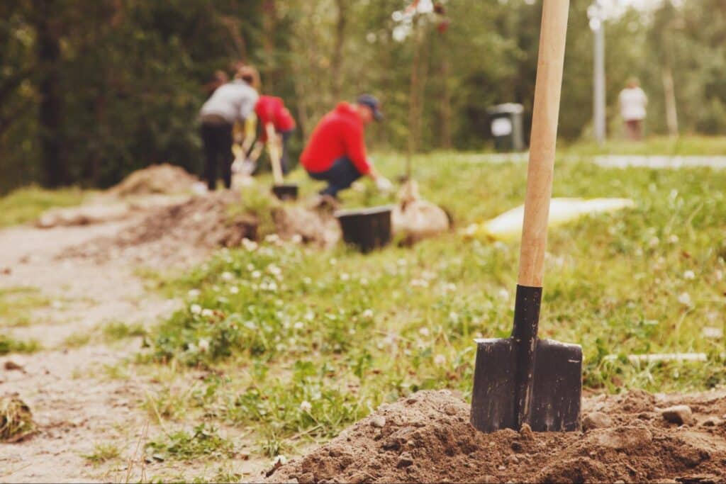 People gardening and digging in a community park for landscaping improvement.