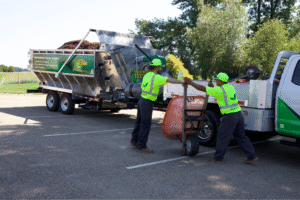 Workers loading organic waste into a truck for eco-friendly disposal and recycling.