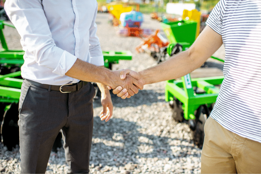 Professionals shaking hands at a construction equipment dealership, symbolizing partnership and trust.