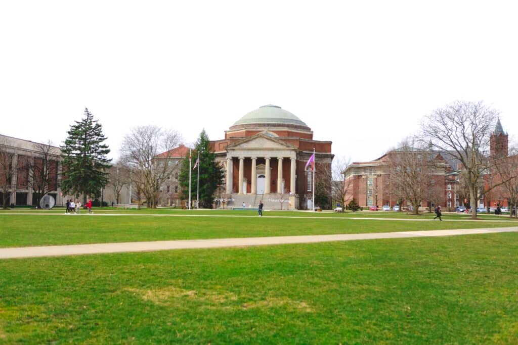 Campus view with historic architecture and students enjoying the green space.