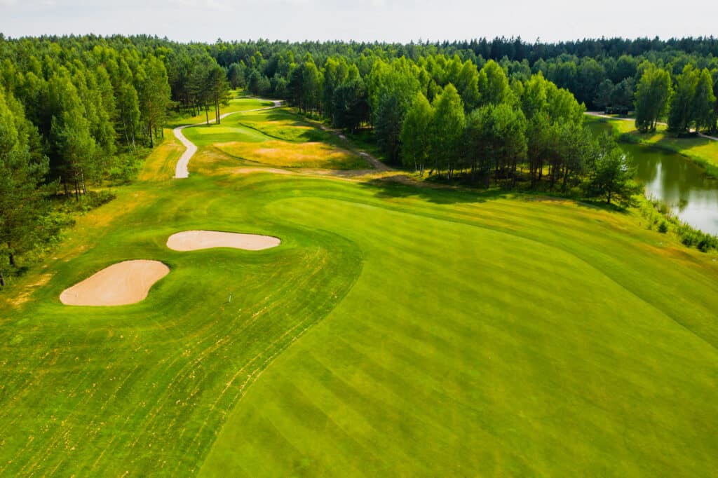 Aerial view of a scenic golf course surrounded by lush wooded areas.