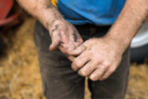 A farmer examines his hands after working, showcasing hard labor and dedication.