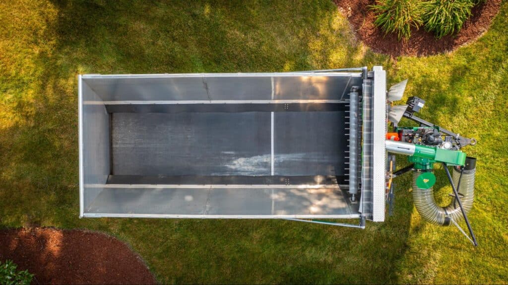 Aerial view of a large, empty landscaping trailer on lush green grass.