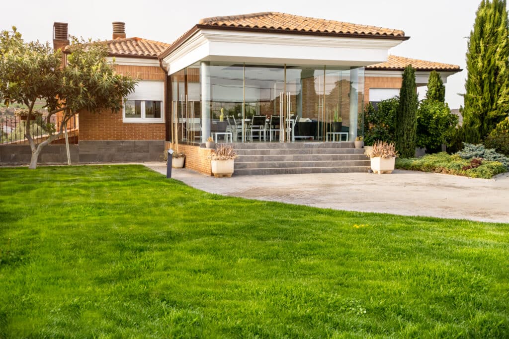Modern family home entry with porch, lush garden, and vibrant green lawn.