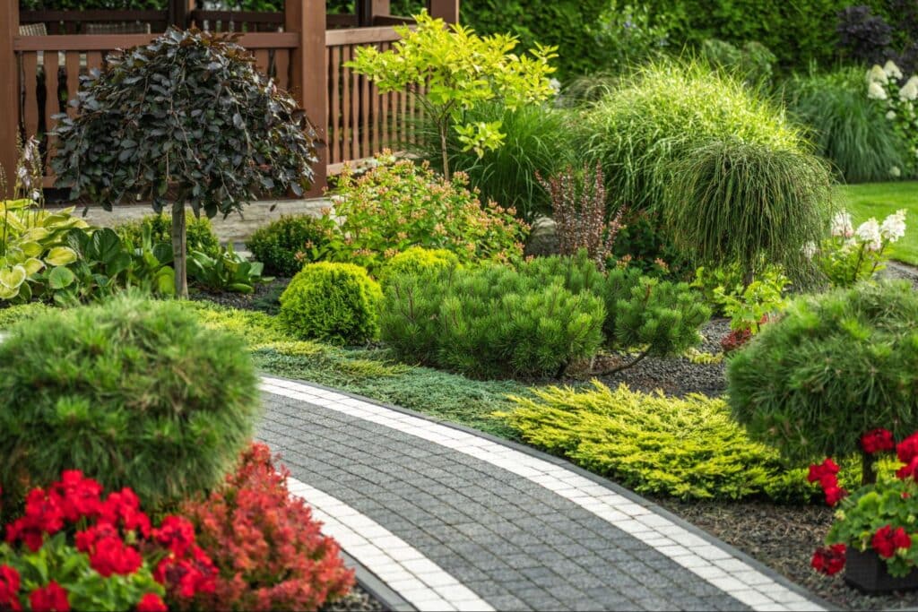 Lush garden pathway surrounded by vibrant flowers and greenery in a serene landscape.