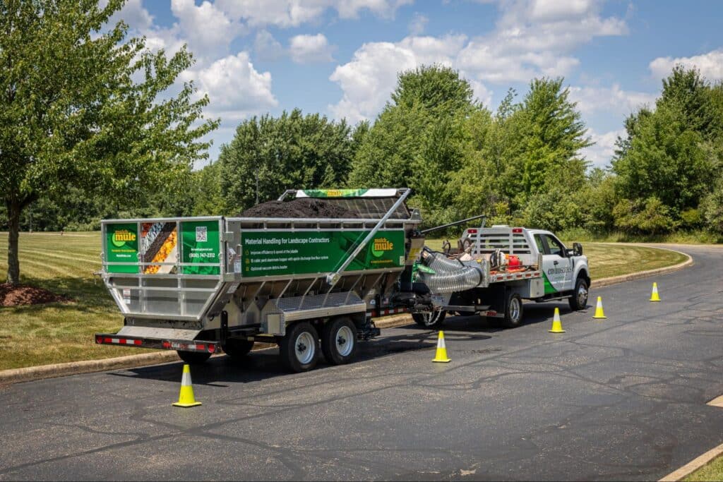 Mulch Mule for sale concept with Mulch Mule trailer filled with landscaping materials parked in a green outdoor setting.