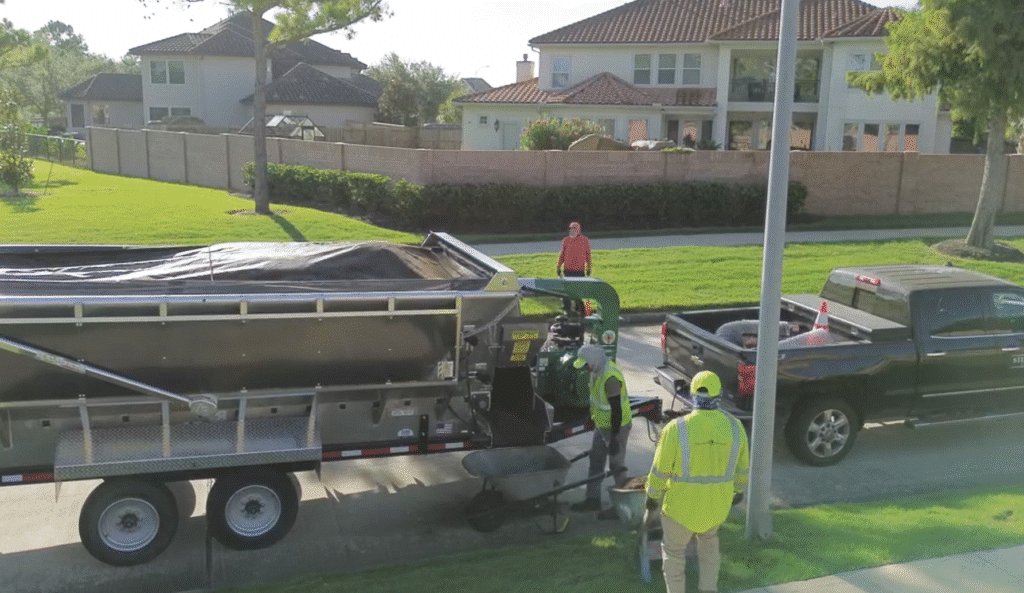 Construction workers unload materials from a Mulch Mule trailer in a residential area.