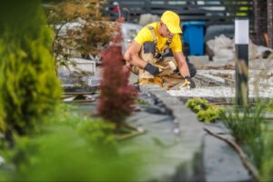 A gardener works on landscape design, planting trees and creating a beautiful outdoor space.
