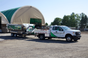 Truck hauling equipment outside a storage facility for construction and landscaping projects.