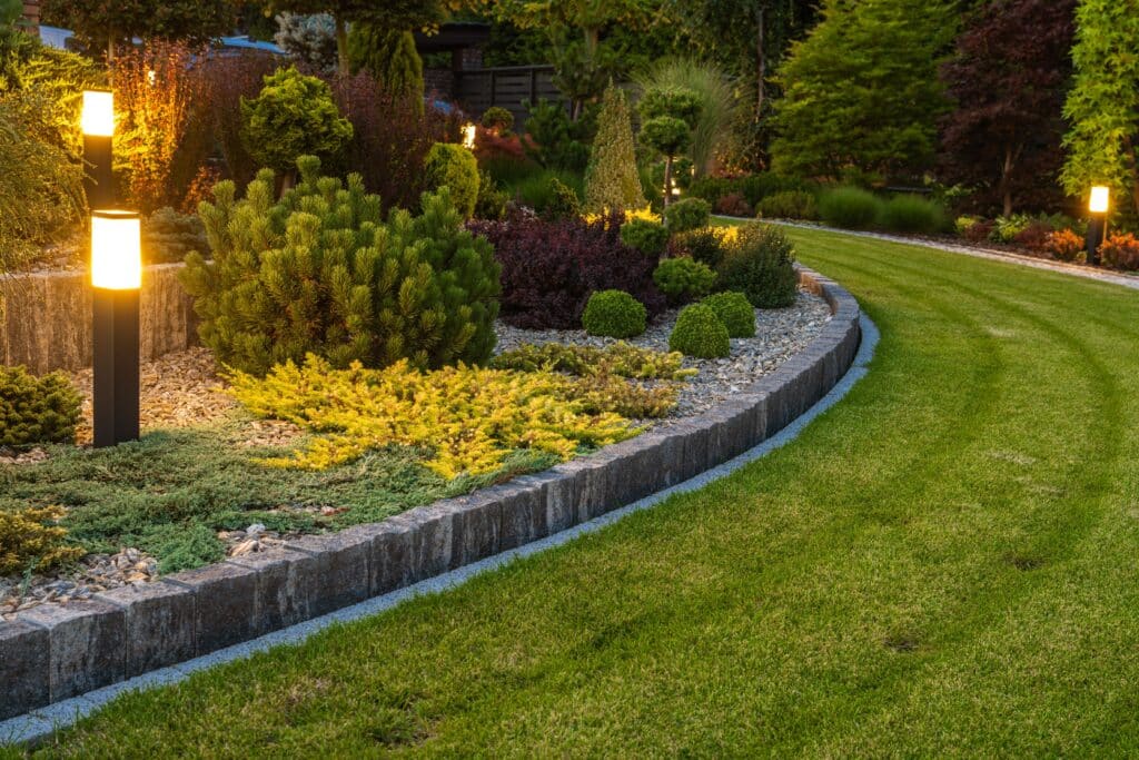 Stylish backyard garden design with illuminated shrubs and well-manicured lawn.