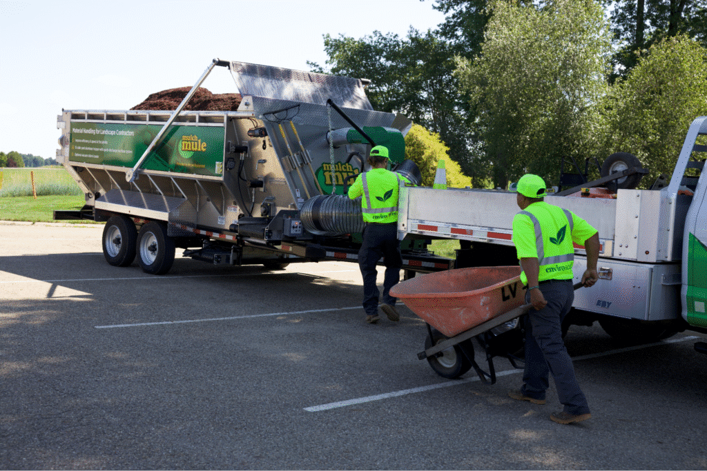 Workers unloading landscaping materials from a Mulch Mule at a job site for efficient maintenance solutions.