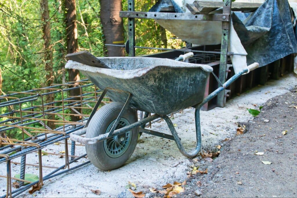 Rustic wheelbarrow on construction site in a wooded area.