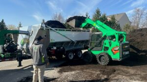 Skid steer loader efficiently loading mulch into a trailer at a mulch yard.