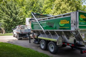 Green Mulch Mule trailer parked, ideal for residential landscaping projects.