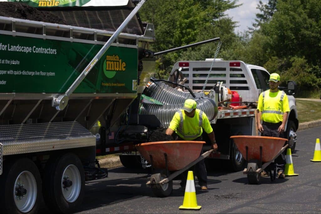 Landscaping crew transporting materials with wheelbarrows for outdoor transformation projects.