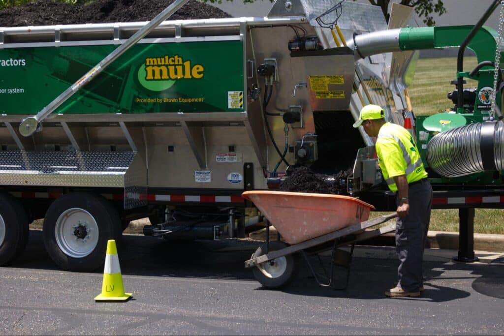 Worker loading mulch into a wheelbarrow for efficient landscaping delivery.